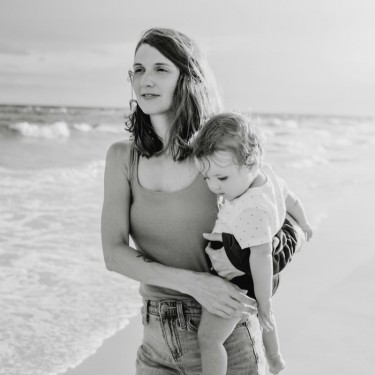 Black and white photo of mom on beach holding toddler