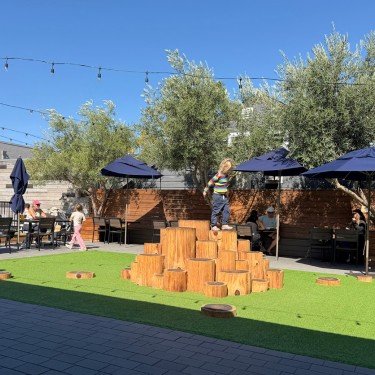 Children playing on wooden climbing structures in the outdoor dining patio at Blue Barn, Novato in Greenbrae, Marin County, a family-friendly restaurant.