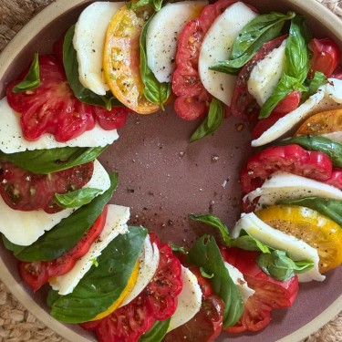 Caprese salad with tomatoes, basil and mozarella arranged on a plate