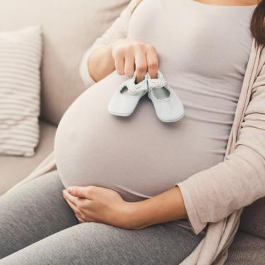 Pregnant woman holding baby shoes