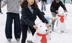 Families enjoying outdoor holiday ice skating at the Union Square ice rink in downtown San Francisco.