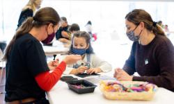 Child working on art project with two teachers