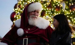 Santa and young girl by Christmas tree