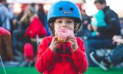 Child in helmet eating a donut