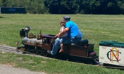 Man and small child riding miniature train in park