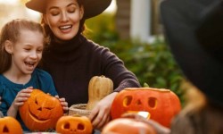 Woman in witch costume and girls at table with pumpkin