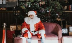 Santa sitting by Christmas tree