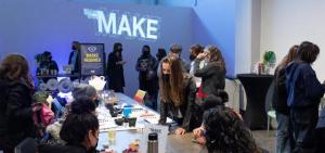 Several people standing and talking, and sitting at a table with art supplies