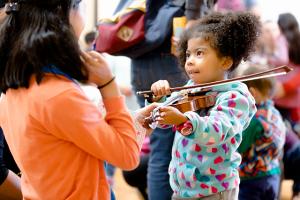 Child playing violin, facing adult