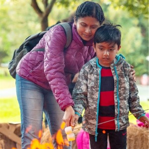 Mom and child roasting marshmallows over campfire in park
