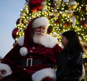Santa and young girl by Christmas tree