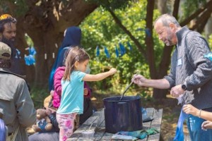 Man and child dying wool in a kettle on a picnic table outdoors
