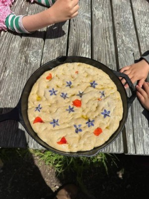 cast iron skillet with colorful dessert held by children