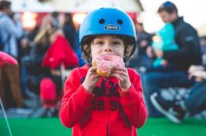 Child in helmet eating a donut