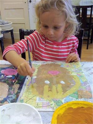 Preschool student painting a self portrait on a collage