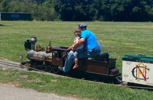 Man and small child riding miniature train in park