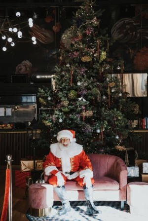 Santa sitting by Christmas tree