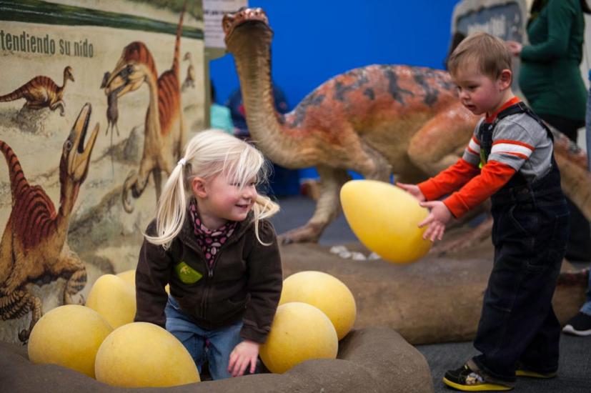 Young children playing in a dinosaur exhibit at the Bay Area Discovery Museum