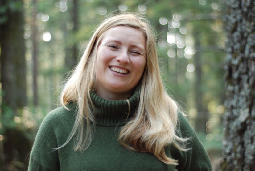Headshot of Jennie Beuhler blonde woman wearing green sweater in forest