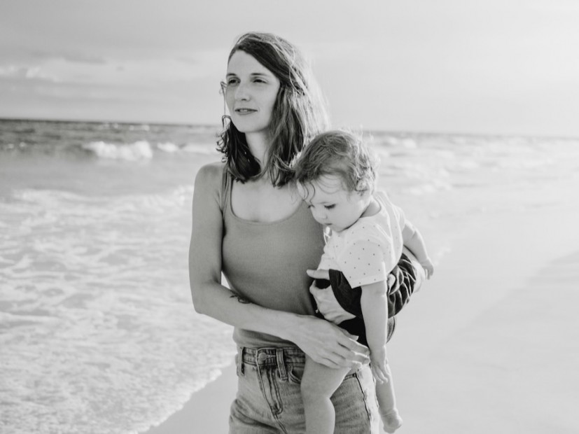 Black and white photo of mom on beach holding toddler