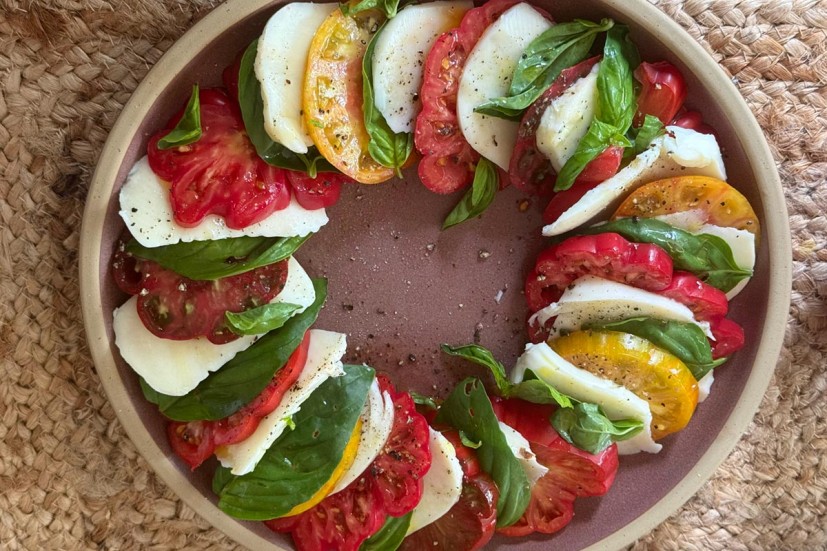 Caprese salad with tomatoes, basil and mozarella arranged on a plate