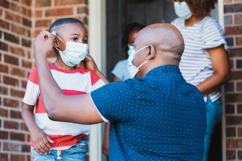 Father helping sone with face mask