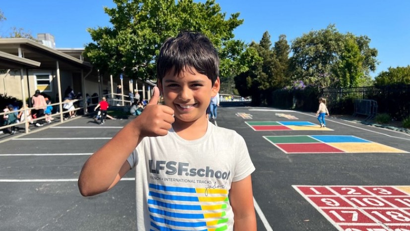 Child at LFSF playground giving thumbs-up