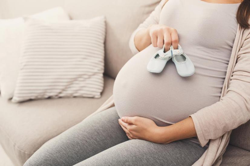 Pregnant woman holding baby shoes