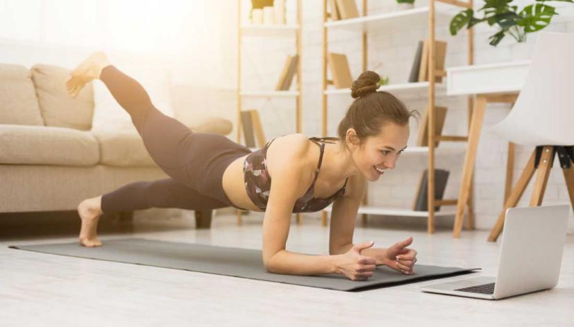 woman doing yoga with a laptop