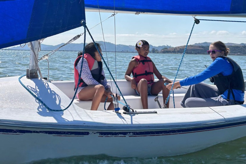 three girls sailing a small sailboat