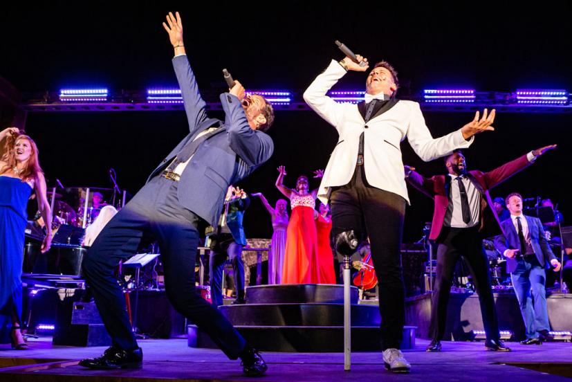 Broadway performers singing and dancing on outdoor stage