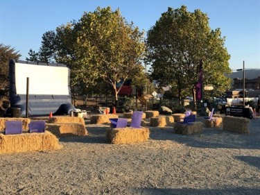 Movie screen set up outside in park with straw bales for seats