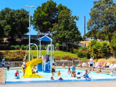 Hamilton Pool kids playing in activity pool with play structure and slide