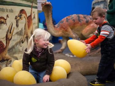 Young children playing in a dinosaur exhibit at the Bay Area Discovery Museum