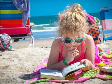 Child reading a book on the beach