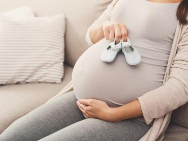 Pregnant woman holding baby shoes