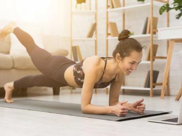 woman doing yoga with a laptop