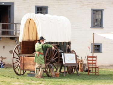 Man in historical costume standing beside a covered wagon at Sutter's Fort State Historic Park